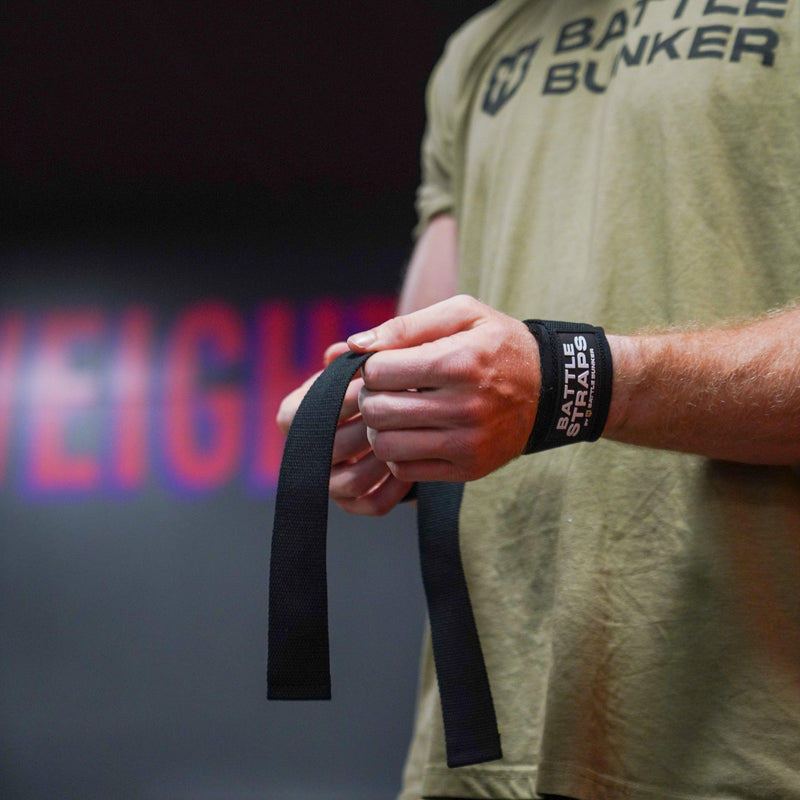 Person wearing Battle Bunker shirt wrapping black Battle Straps wrist wraps for weightlifting
