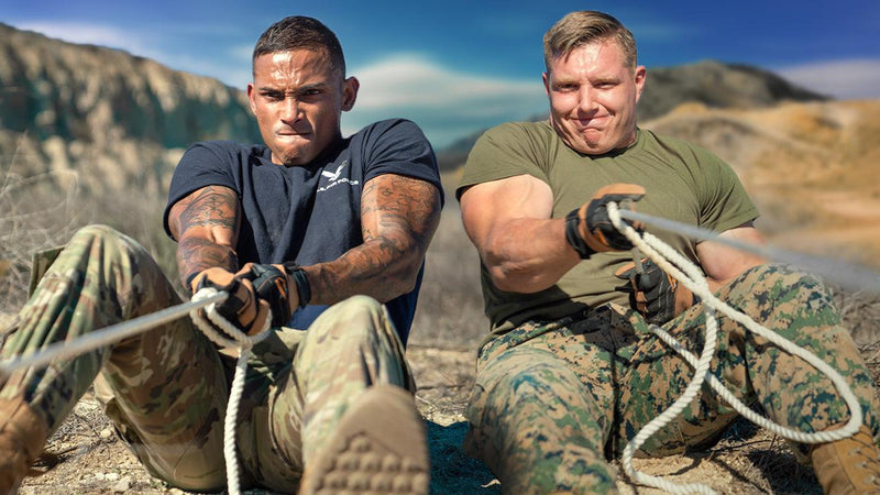 Two soldiers in battle bunker training pulling ropes with intense focus in outdoor rugged terrain