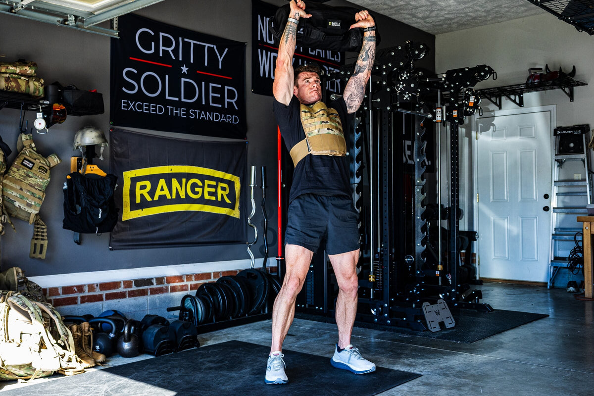 Dan Fahey of Gritty Soldier pressing a sandbag overhead in his garage gym