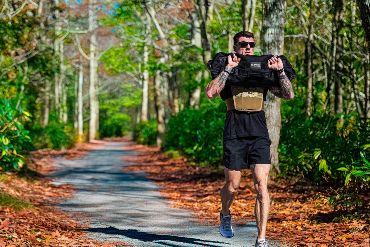 Dan Fahey of Gritty Soldier carrying a sandbag down a wooded road