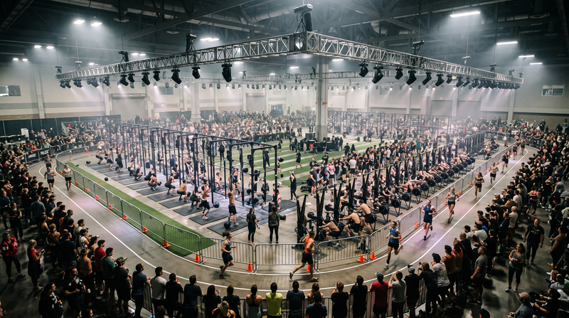 Wide view of a fitness race in a huge exhibition hall with a running loop around the stations