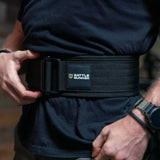Close-up of person wearing a black Battle Bunker weightlifting belt securing it around the waist
