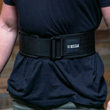 Close-up of a person wearing a black Battle Bunker branded weightlifting belt over a black shirt