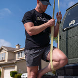 Man in Battle Bunker t-shirt adjusting strap against blue sky near Battle Bunker camo vehicle