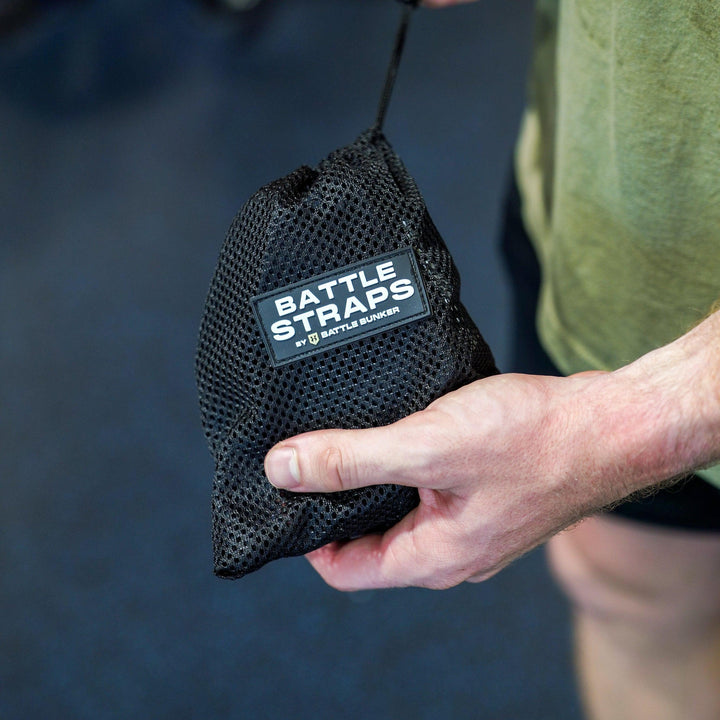 Hand holding a black mesh pouch labeled Battle Straps by Battle Bunker