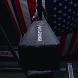 Battle Bunker heavy black punching bag hanging in gym with American flag background
