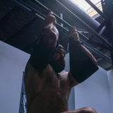 Muscular man training upper body with arm straps on metal bars in industrial battle bunker gym