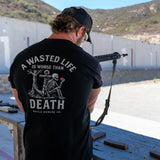 Man at outdoor shooting range wearing black Battle Bunker t-shirt with skeleton and phrase, aiming rifle
