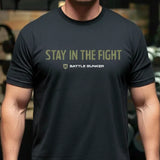 Man wearing black Battle Bunker t-shirt with Stay In The Fight slogan in gym setting