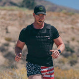 Man wearing Battle Bunker tactical vest and cap jogging in desert with American flag shorts