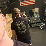 Man wearing Battle Bunker black T-shirt with skeleton soldier design in gym with weights and American flag