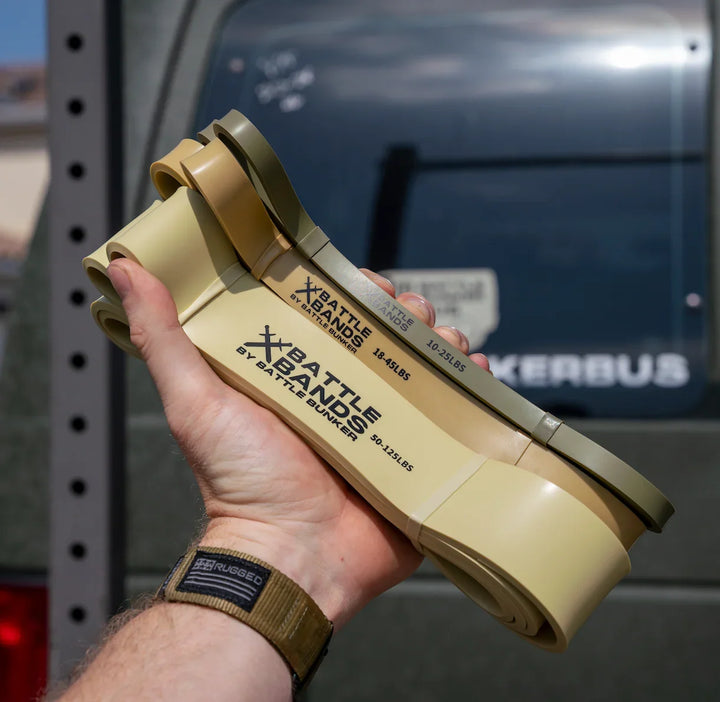 Hand holding three loops of Battle Bands resistance bands by Battle Bunker in different strengths