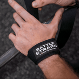 Close-up of hand wearing Battle Straps wrist wrap by Battle Bunker gripping a barbell in gym