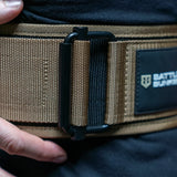 Close-up of tan Battle Bunker tactical belt buckle and strap with black stitching and logo patch