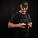 Man wearing black Battle Bunker tactical vest and cap on black background