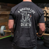 Man wearing black Battle Bunker T-shirt with skeleton holding apple and text about wasted life and death