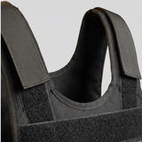 Black tactical vest with visible branding on a light gray background