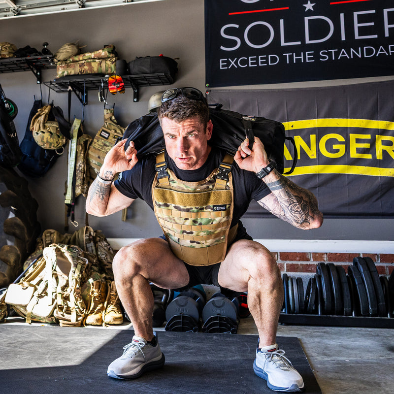 Dan Fahey of Gritty Soldier doing a sandbag squat in the Battle Bunker Hybrid Weight Vest MK2 camo