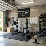 Home gym with weight rack, barbells, kettlebells, rowing machine, and Battle Bunker motivational banner