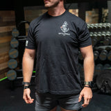 Man wearing black Battle Bunker t-shirt with skeleton and anchor logo in gym setting